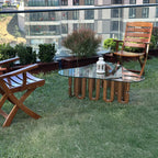 Design-Couchtisch von fofofu aus recyceltem Holz mit Glasplatte und wellenförmigem Gestell – handgefertigtes Möbelstück im modernen Gartenambiente mit Holzstühlen und Stadtblick.